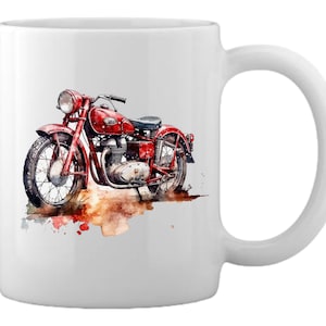 May include: White ceramic mug with a watercolor illustration of a red vintage motorcycle. The motorcycle has a brown leather seat and is surrounded by brown and orange watercolor splatters.