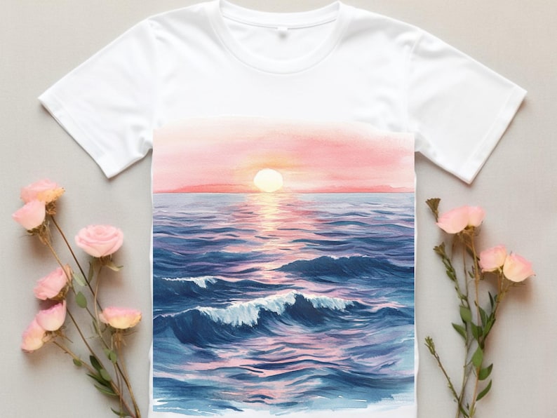 K&ouml;nnte beinhalten: Ein wei&szlig;es T-Shirt mit einem Aquarellbild eines Sonnenuntergangs &uuml;ber dem Meer. Das Bild zeigt einen rosa und orangenen Himmel, ein blaues Meer mit Wellen und eine strahlend gelbe Sonne.