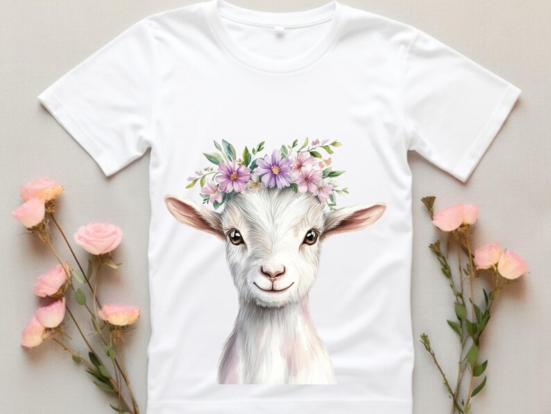 May include: White t-shirt with a watercolor illustration of a goat wearing a flower crown. The goat has a white face with pink accents and a pink nose. The flowers in the crown are pink and purple.