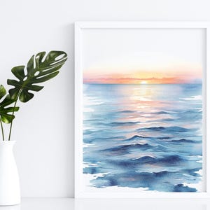 K&ouml;nnte beinhalten: Ein Aquarellgem&auml;lde eines Sonnenuntergangs &uuml;ber dem Meer. Das Wasser ist tiefblau mit einem Hauch von Rosa und Orange von der untergehenden Sonne. Der Himmel ist zartrosa und orange.