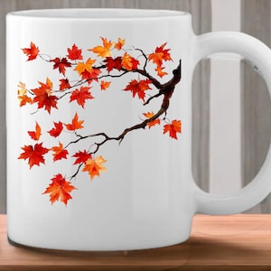 K&ouml;nnte beinhalten: Wei&szlig;e Keramiktasse mit einem Design aus einem Zweig mit orangefarbenen und roten Bl&auml;ttern. Die Bl&auml;tter sind in Aquarelltechnik gemalt.