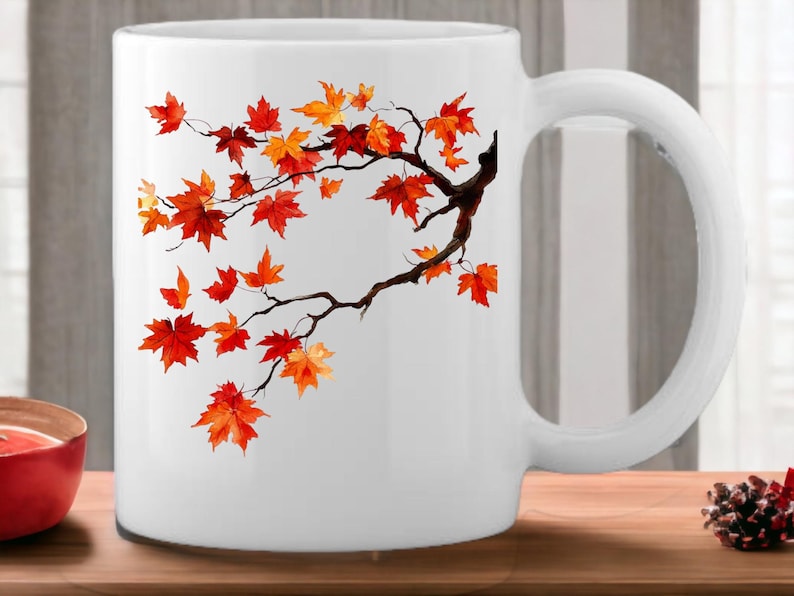 K&ouml;nnte beinhalten: Wei&szlig;e Keramiktasse mit einem Design aus einem Zweig mit orangefarbenen und roten Bl&auml;ttern. Die Bl&auml;tter sind in Aquarelltechnik gemalt.