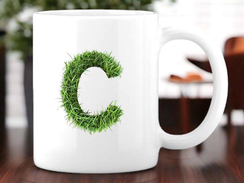 May include: White ceramic mug with a green grass letter C design.