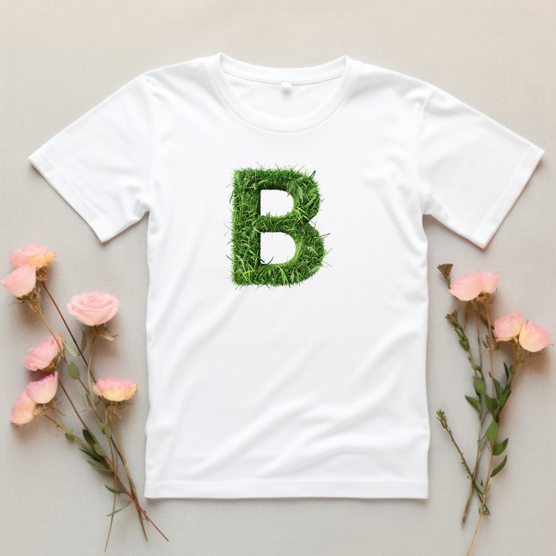 May include: White t-shirt with a green letter "B" made of grass.