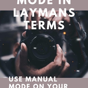 May include: Image with text: "MANUAL MODE IN LAYMANS TERMS" and "USE MANUAL MODE ON YOUR SLR THE EASY WAY." A person is holding a black camera, with the lens facing the viewer. The background is blurred, with a muted color palette.