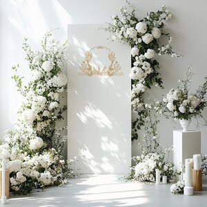 May include: A white backdrop decorated with white flowers and greenery, featuring a gold ornate frame with a blank space in the center.