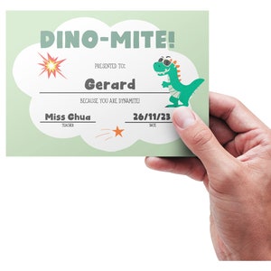 May include: A green dinosaur wearing sunglasses and a bandage is on a light green certificate with the text "DINO-MITE!" and "PRESENTED TO Gerard BECAUSE YOU ARE DYNAMITE!"  The certificate also includes the text "Miss Chua TEACHER" and "26/11/23 DATE".