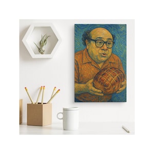 May include: A framed canvas art print featuring a portrait of a man with glasses holding a ham. The artwork has a textured, painterly style with a blue and orange color palette. The print is displayed on a white wall.