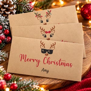 May include: Three rectangular kraft paper envelopes stacked vertically. Each envelope features a different reindeer illustration: one with Christmas lights in its antlers, one with a red bow, and one with black sunglasses. The bottom envelope says Merry Christmas Amy.