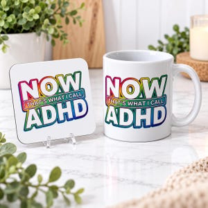 May include: A white ceramic mug and a square coaster, both featuring the colourful text "NOW THAT'S WHAT I CALL ADHD" in a bold, rainbow-gradient font. The design is centred on both items, showcasing a vibrant, multi-coloured outline.