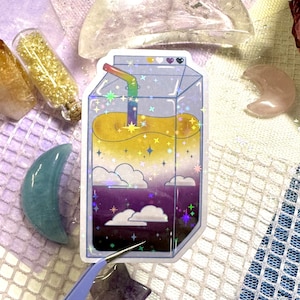 May include: A holographic sticker of a cartoon juice box with a rainbow straw, yellow liquid, and clouds with stars in the background.
