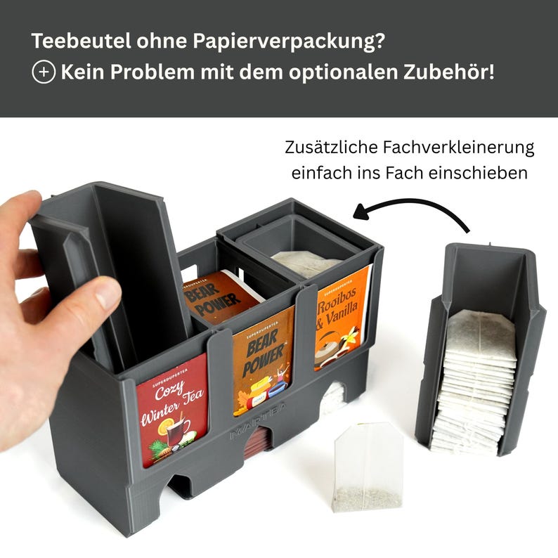 Op de afbeelding: Een donkergrijze theezakjes-organizer van kunststof met meerdere vakken. De unit is voorzien van uitneembare verdelers om de ruimte aan te passen. Theezakjes zijn zichtbaar in de vakken, inclusief labels zoals Cozy Winter Tea, Bear Power en Rooibos & Vanilla.