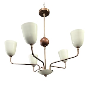 May include: A mid-century modern chandelier with five off-white glass shades. The fixture has a bronze finish with a wooden sphere accent. The arms extend from a central base, creating a balanced and elegant design.