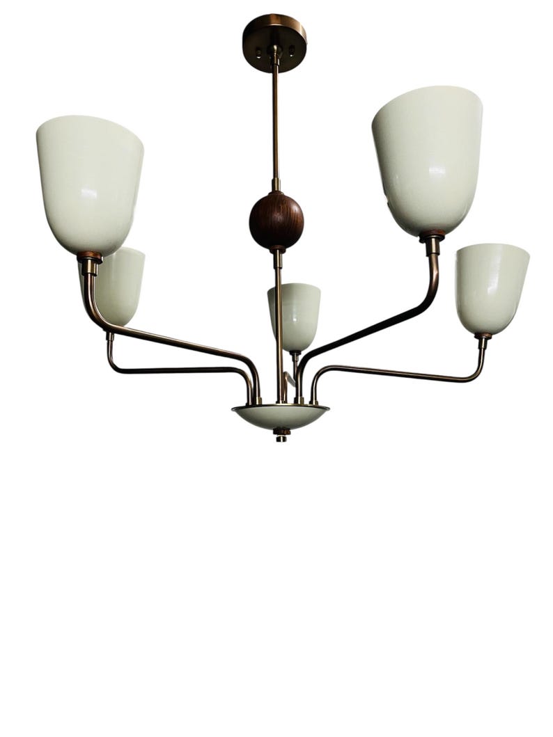 Puede incluir: Un candelabro de estilo vintage con cinco pantallas de vidrio blanco en forma de tulip&aacute;n. La l&aacute;mpara tiene un acabado de bronce con un elemento de madera oscura. Los brazos se extienden desde un punto central, creando un dise&ntilde;o equilibrado y elegante.