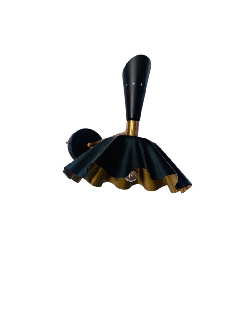 Op de afbeelding: Een zwart en goudkleurige wandlamp met een uniek ontwerp. De lamp heeft een zwarte, kegelvormige top met kleine decoratieve gaatjes. De kap is donkergroen met een gerimpelde rand en een gouden binnenkant. De lamp is gemonteerd op een zwarte, cirkelvormige basis.