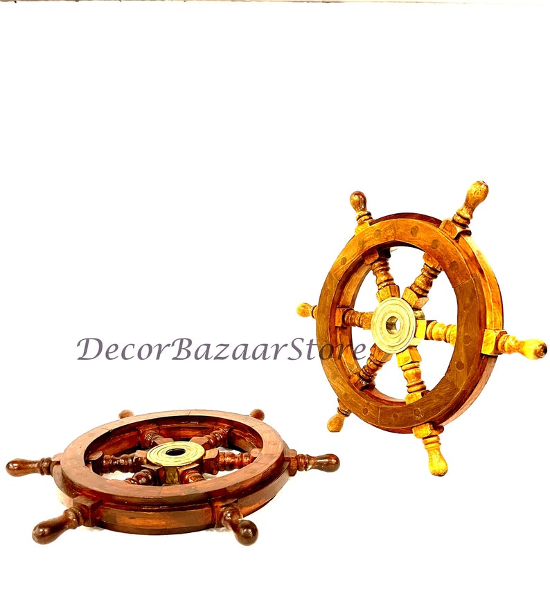 May include: Two wooden ship steering wheels with brass accents. The larger wheel is on the right and the smaller wheel is on the left. Both wheels have a dark brown finish.
