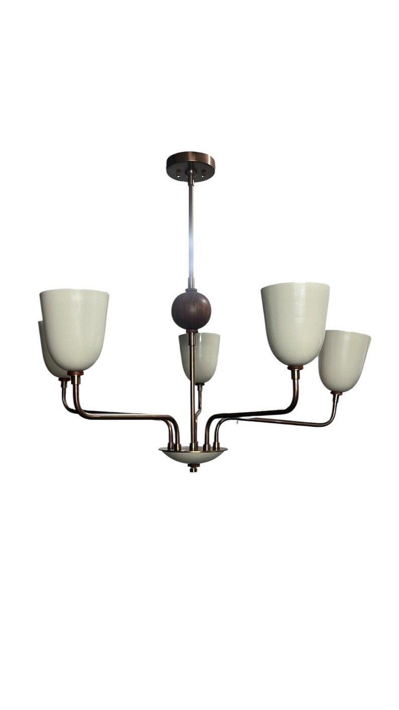 Puede incluir: Una l&aacute;mpara de ara&ntilde;a de estilo retro con cinco pantallas en forma de tulip&aacute;n de color blanco roto. La l&aacute;mpara tiene brazos y un v&aacute;stago de color bronce, una esfera de madera oscura y una peque&ntilde;a base decorativa. El dise&ntilde;o es minimalista y elegante.