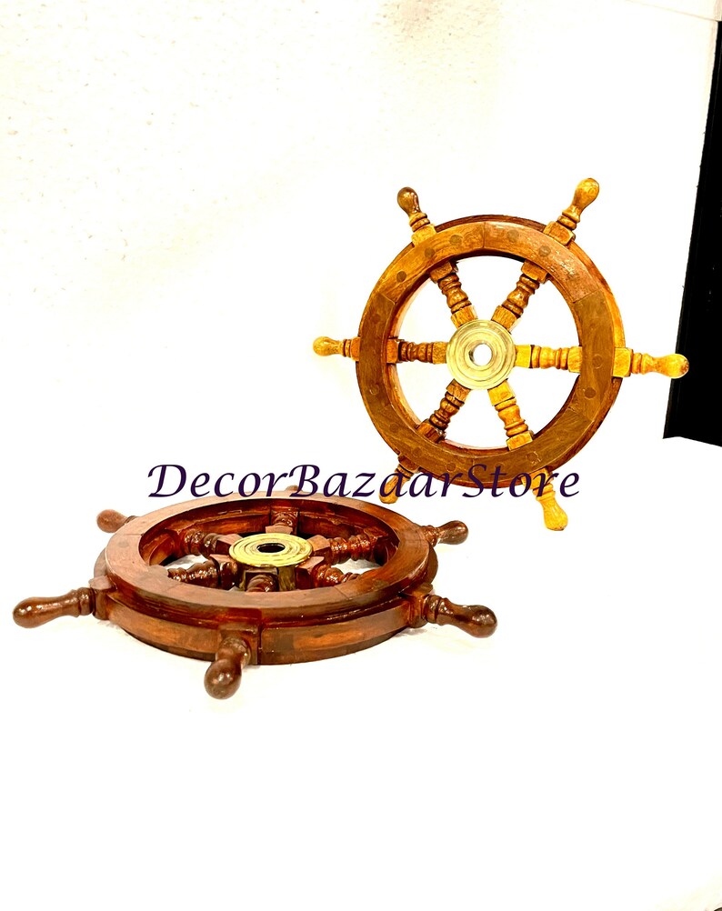May include: Two wooden ship steering wheels with brass accents. The wheels are brown with a light brown wood grain. The wheels have six spokes and a brass center hub. The wheels are on a white background.