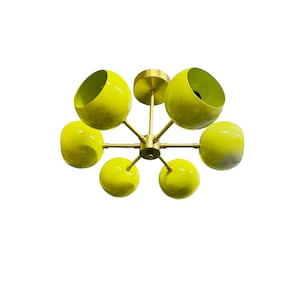May include: A yellow, six-light chandelier with a brass frame. The light bulbs are enclosed in round, yellow glass shades.