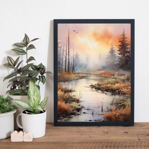 May include: A framed watercolor painting depicting a misty forest scene with a winding river in the foreground. The sky is a soft orange and pink, with a few birds flying overhead. The trees are silhouetted against the sky, and the water is a reflective blue.
