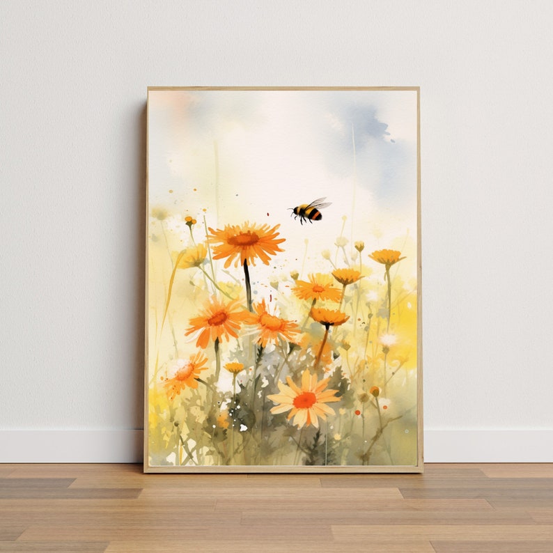 May include: Watercolor painting of a field of orange daisies with a flying bee. The artwork is framed in a light wood frame. The background is a soft blend of yellow, white, and blue.