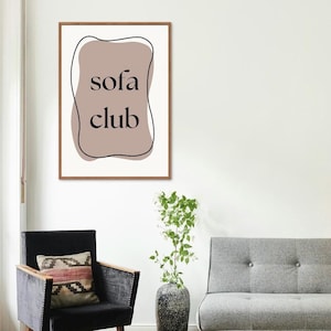 May include: A framed print with a brown background and black text that reads "sofa club". The print is in a modern style and would look great in a living room or bedroom.