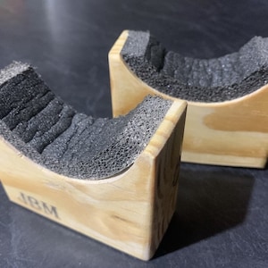 May include: Two wooden blocks with a foam lining, each with the letters "JBM" engraved on the bottom.