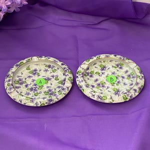 May include: A white ceramic mug with a black handle and the text "But First, Coffee" in a bold, black font. The mug is set against a blurred background, suggesting a cozy setting.