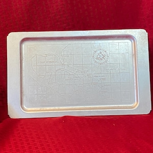 May include: A silver metal tray with a map of the Caribbean Sea and surrounding islands. The tray has a compass rose and the text "GULF OF MEXICO" and "ATLANTIC OCEAN".