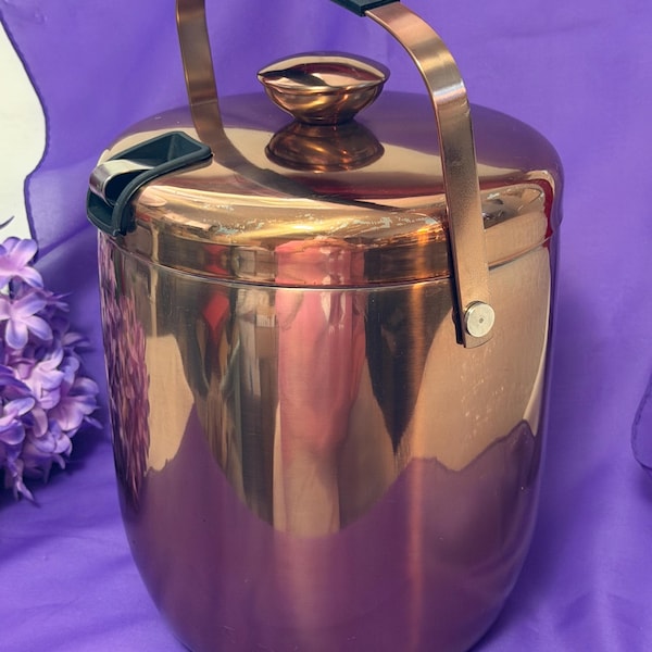 Malmo double walled stainless steel ice bucket with matching lid and built in utility tongs holder. Polished copper exterior finish.