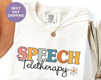 May include: Ivory t-shirt with the text "SPEECH Teletherapy" in colorful letters and a small flower graphic. The text is in a retro style font.