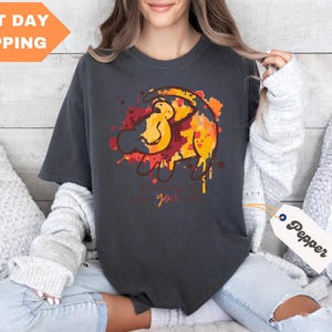 a woman sitting on a bed wearing a t - shirt with a lion on it