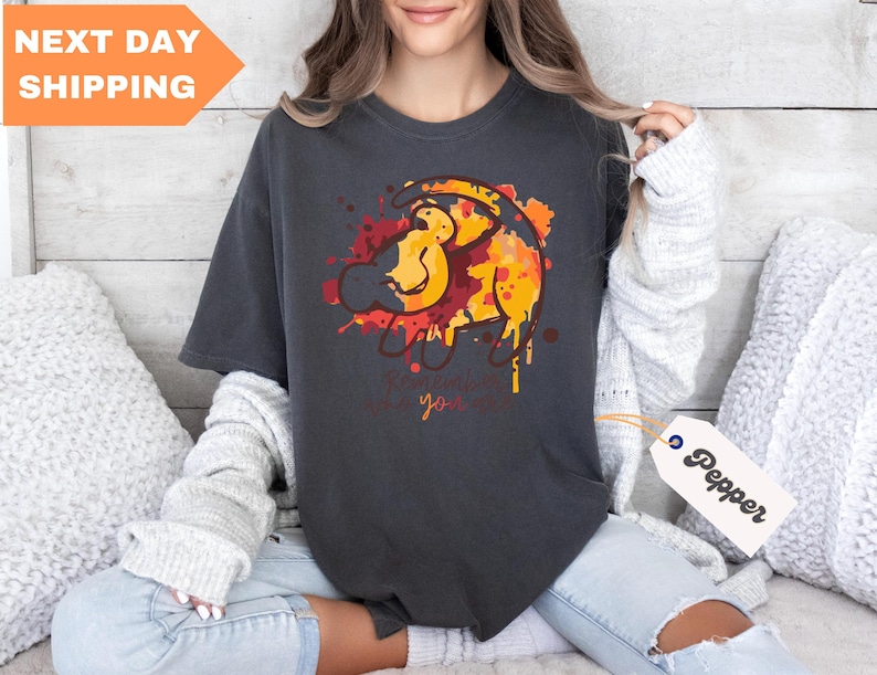 a woman sitting on a bed wearing a t - shirt with a lion on it