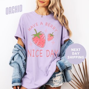 a woman wearing a purple shirt with a strawberry on it