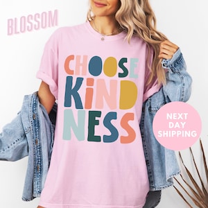 a woman wearing a pink t - shirt that says choose kind of nesss next