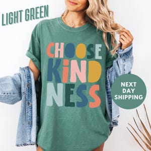 a woman wearing a t - shirt that says choose kind of nesss next to