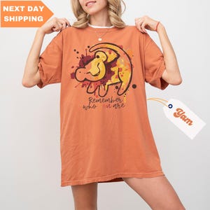 a woman is holding up a t - shirt with a lion on it
