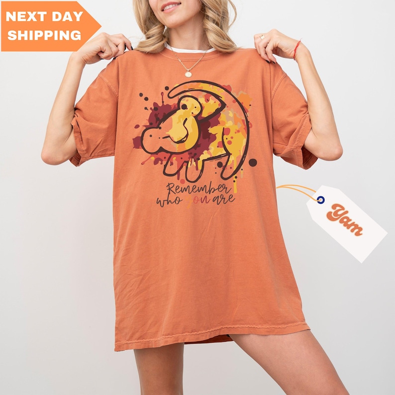 a woman is holding up a t - shirt with a lion on it