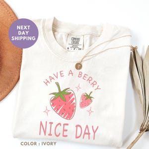 a t - shirt that says have a berry nice day next to a straw hat