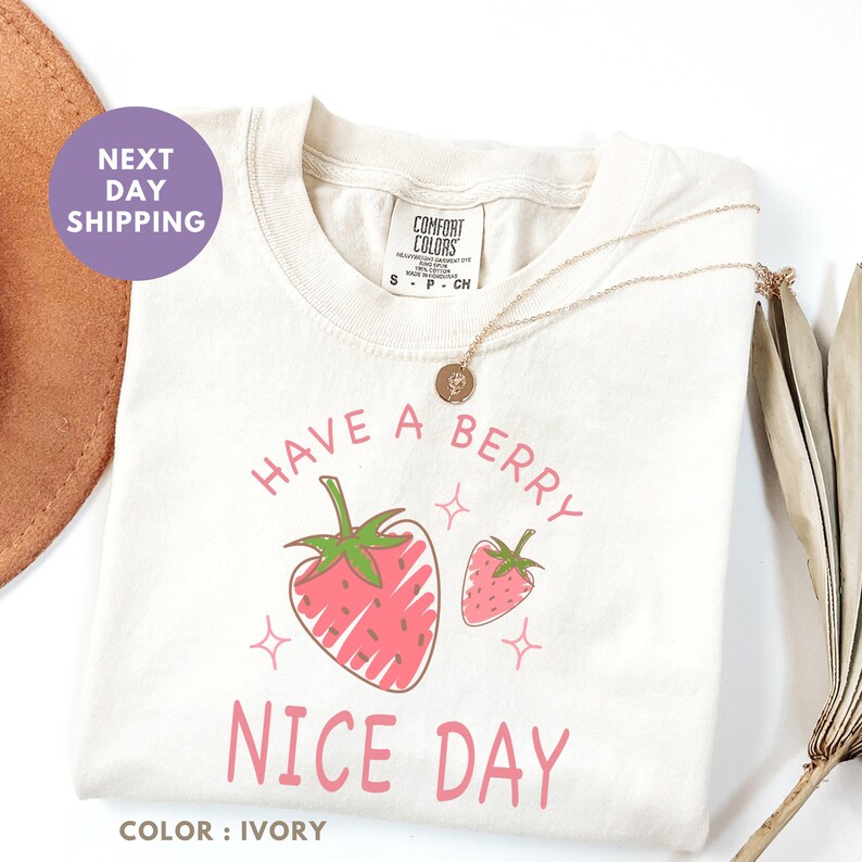 a t - shirt that says have a berry nice day next to a straw hat