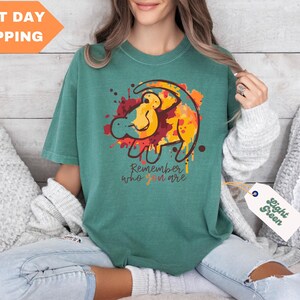 a woman sitting on a bed holding a t - shirt