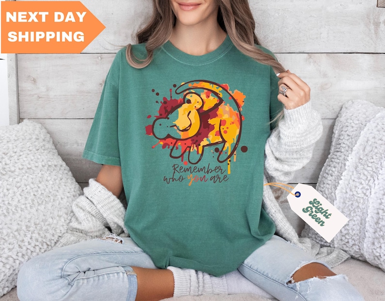 a woman sitting on a bed holding a t - shirt