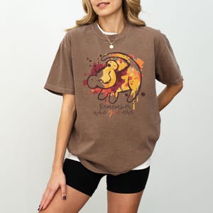 a woman wearing a brown shirt with a lion on it