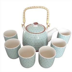 May include: A green and white tea set with a teapot and six cups. The teapot has a bamboo handle and a geometric pattern. The cups have the same geometric pattern.