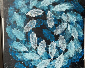 Peut inclure: Une peinture abstraite bleue et blanche sur une toile noire. La peinture présente un motif circulaire de feuilles blanches sur un fond bleu. L'arrière-plan est parsemé de peinture blanche.