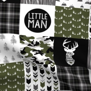 May include: A patchwork fabric design featuring various patterns in shades of black, white, and olive green. The design includes plaid, camouflage, deer antlers, arrows, trees, and the text "LITTLE MAN" in a black circle. The phrase "YOU ARE SO DEEPLY LOVED" is also present.