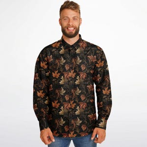 Può includere: Una camicia a maniche lunghe con bottoni, sfondo scuro e motivo di foglie marroni e arancioni.