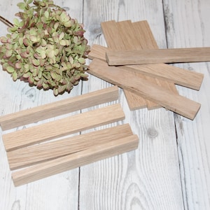May include: A set of four unfinished wooden rectangular blocks, stacked on top of each other. The blocks are made of light-colored wood and have a smooth surface.
