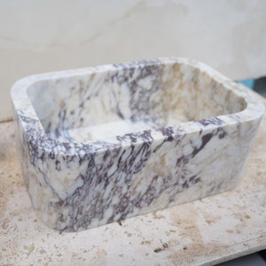 Luxury handcrafted Calacatta Viola marble floating wall mounted bathroom sink with fluted front in a premium designer bathroom.