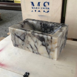 Calacatta Viola marble wall-mount sink with stunning natural veining. Handcrafted floating stone basin with no overflow, single faucet hole. Perfect for luxury bathrooms, interior designers, boutique hotels, and modern renovations. Ideal as a vessel sink, bar sink, or designer washbasin. Unique Italian marble sink for minimalist, high-end bathrooms. Trending marble bathroom decor, handcrafted stone sink.